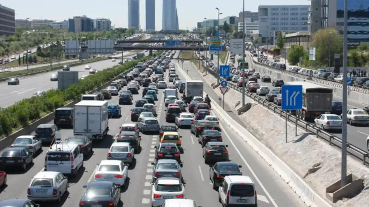 Congestión vehicular en una autopista, reflejo de la movilidad urbana. Coches y camiones detenidos en múltiples carriles bajo un cielo despejado.