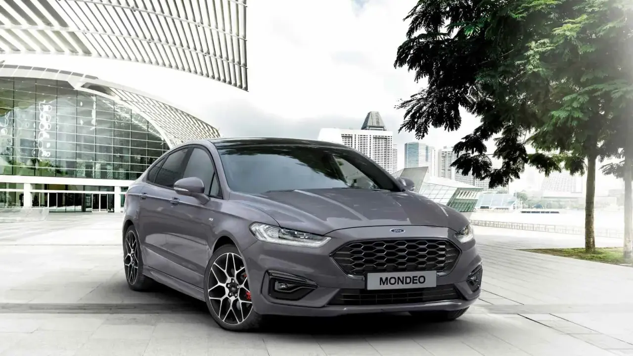 Ford Mondeo gris aparcado frente a un edificio moderno. Las medidas del Ford Mondeo son ideales para la ciudad.