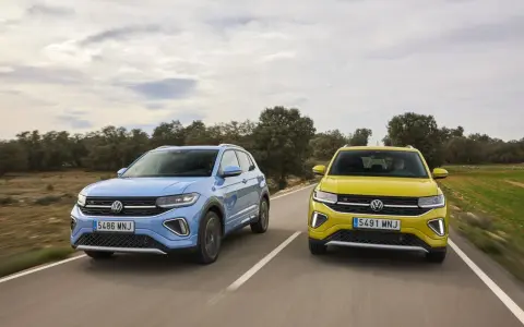 Un Volkswagen T-Cross azul y un T-Roc amarillo circulan por una carretera rural.