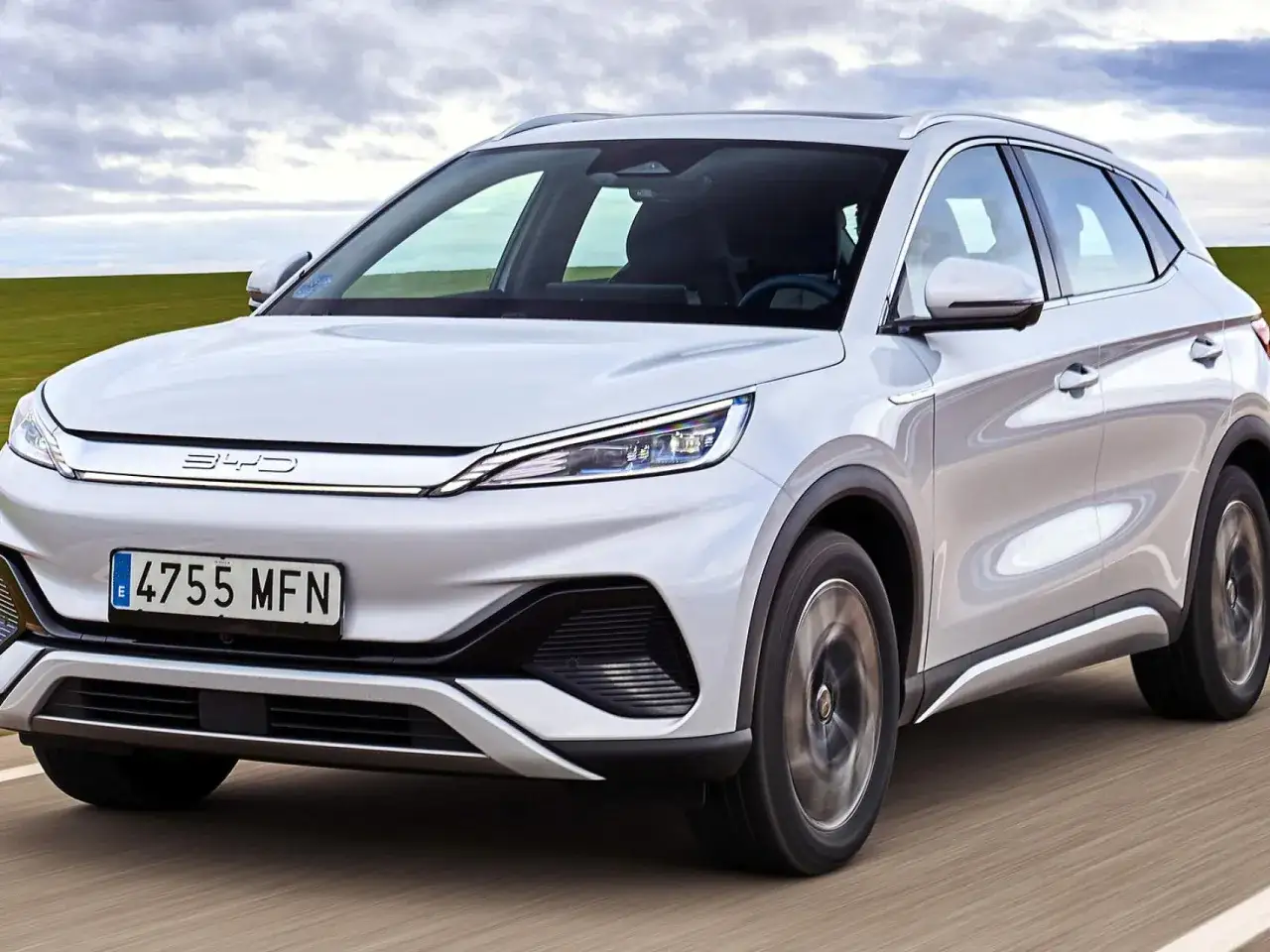 Un SUV blanco BYD, con el logo en el frontal, circula por una carretera. El BYD significado es 