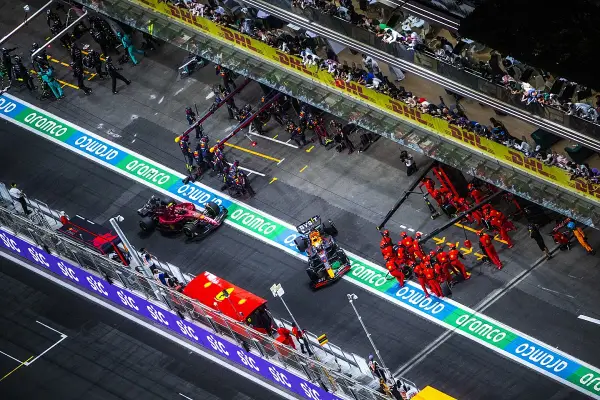 Equipos de F1 en boxes. Un coche Red Bull con un undercut f1 se detiene, mientras mecánicos de Ferrari se preparan.